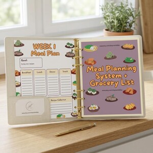 Peut inclure: Un classeur beige ouvert, avec des anneaux dorés, présentant des pages de planification des repas. La page de gauche indique "Week 1 Meal Plan" avec des sections pour les repas. La page de droite dit "Meal Planning System + Grocery List."