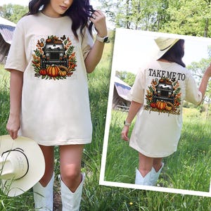 Może przedstawiać: Duża, beżowa koszulka z nadrukiem czarnego jeepa ozdobionego dyniami i jesiennymi liśćmi. Z tyłu koszulki napis "Zabierz mnie na pole dyni".