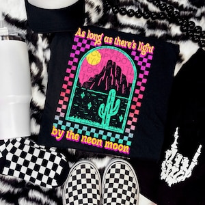 May include: Black t-shirt with a graphic of a desert landscape with a cactus and the text "As long as there's light by the neon moon".
