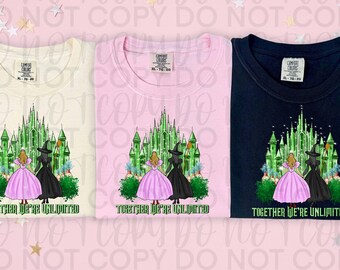 May include: Three t-shirts with a graphic print of the Emerald City from the Wizard of Oz. The graphic features two women, one in a pink dress and one in a black dress, standing in front of the castle. The text "Together We're Unlimited" is printed below the graphic.