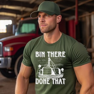 May include: A green t-shirt with a white graphic of a grain silo and the text "Bin There Done That". The model is wearing a green baseball cap.