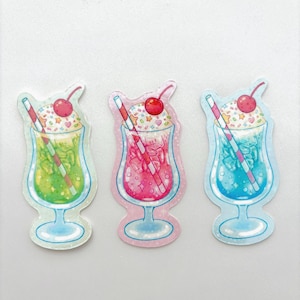 May include: Three colorful soda stickers. Each sticker features a different colored soda in a glass with a cherry on top and a striped straw. The soda colors are green, pink, and blue.