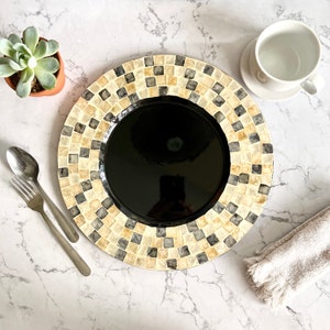 May include: A black and white mosaic charger plate with a black center. The charger plate is made of ceramic and has a glossy finish.