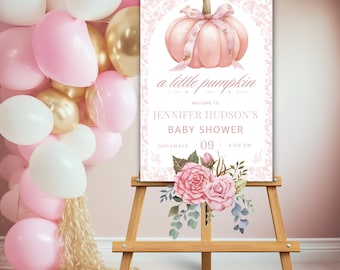 May include: A pink and white baby shower sign featuring a pink pumpkin and floral decorations. The sign reads "a little pumpkin is on the way!" and "Jennifer Hudson's Baby Shower" with the date and time.