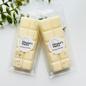 May include: Two packs of wax melts in clear plastic packaging. Each pack contains six square wax melts. The wax melts are a light yellow colour and have a white label with the text "A Scents of Adventure Mitzee's Melts Soapy Doves".