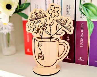 Bouquet of flowers and books in engraved teacup pot with its base