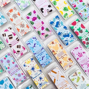 K&ouml;nnte beinhalten: Eine Sammlung rechteckiger Wachsschmelz-Verpackungen, die jeweils einzigartige bunte Muster und Etiketten wie Aloha Lobby, Night Blossom, Banshee Flight, Magical Waffles und Candy Emporium aufweisen und in durchsichtigen Kunststoffbeh&auml;ltern verpackt sind.