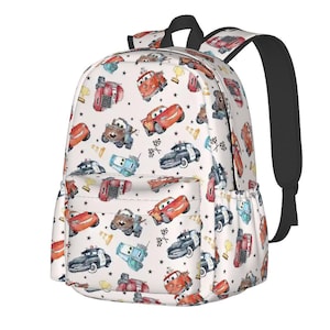 May include: White backpack with a repeating pattern of cartoon cars in various colours. The backpack has black straps and a black handle. The design includes race flags, trophies, and stars. It has a front and side pocket.