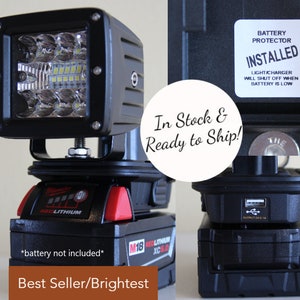 May include: A black LED light with a clear lens and multiple LEDs. The light is mounted on a black base with a red and black Milwaukee M18 battery pack. The battery pack has a USB port and a label that says "RED LITHIUM XC 5.0". The light has a sticker that says "BATTERY PROTECTOR INSTALLED LIGHT/CHARGER WILL SHUT OFF WHEN BATTERY IS LOW". The text "In Stock & Ready to Ship!" is written in white on a black circle. The text "Best Seller/Brightest" is written in white on a brown rectangle.