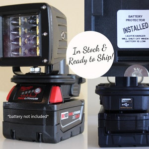 May include: A black and red Milwaukee M18 REDLITHIUM XC 5.0 battery powered LED work light with a 10-LED array. The light is mounted on a black bracket and has a USB charging port. The battery is not included. The sticker on the light reads "Battery Protector Installed. Light/Charger will shut off when battery is low."