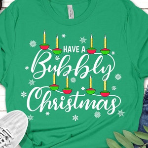 May include: A green t-shirt with the text "Have a Bubbly Christmas" in white lettering. The design features a row of stylized candles with red and green accents.