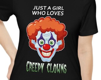 May include: Black t-shirt with white text that reads "Just a girl who loves creepy clowns". A cartoon image of a creepy clown with red hair, blue eyes, and a big smile is in the center of the shirt.