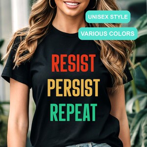 May include: Black t-shirt with the text "Resist Persist Repeat" in red, yellow, and green. The text is stacked vertically. Unisex style, available in various colors.