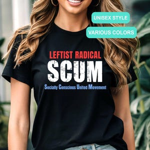 May include: Black t-shirt with the words "LEFTIST RADICAL SCUM" in white, and "Socially Conscious United Movement" in blue. The text is distressed. The shirt also has the text "UNISEX STYLE" and "VARIOUS COLORS" in a light blue box.