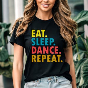 May include: Black t-shirt with the text "EAT. SLEEP. DANCE. REPEAT." in colorful letters.