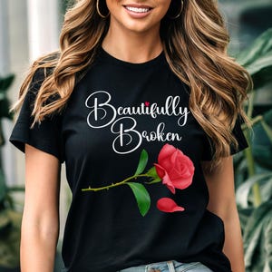 Puede incluir: Camiseta negra con el texto "Beautifully Broken" en letras blancas y una rosa roja con hojas verdes.