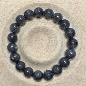 Pode incluir: Um bracelete de pedras preciosas azul escuro com contas redondas. O bracelete &eacute; feito de pedras naturais e tem aproximadamente 20 cm de comprimento.