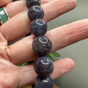 Pode incluir: Um bracelete de contas cinza escuro com contas redondas e lisas. As contas t&ecirc;m um brilho ligeiramente iridescente.