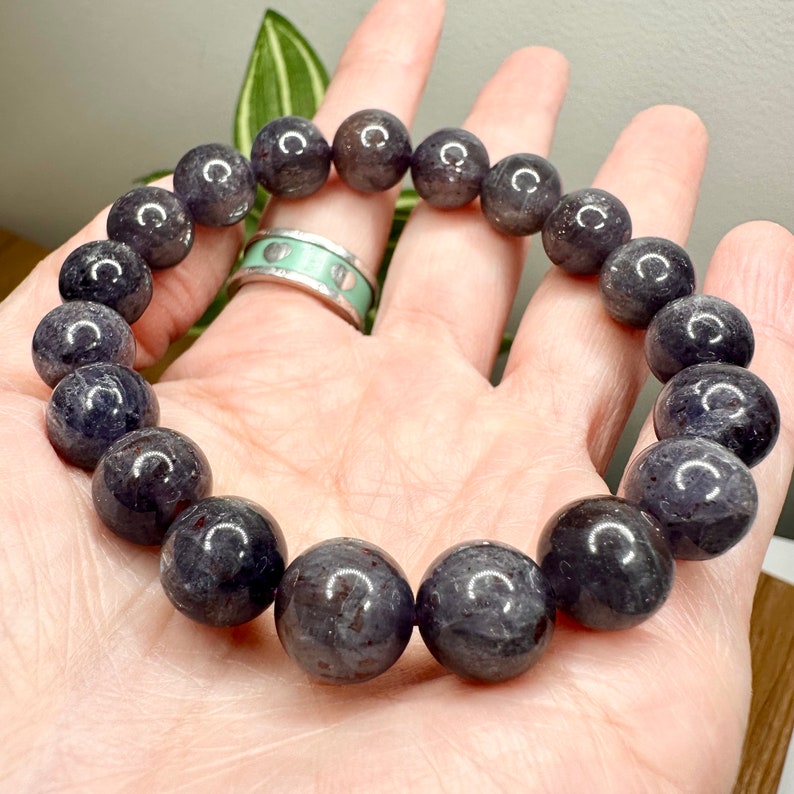Pode incluir: Um bracelete de pedras preciosas cinza escuro com contas redondas. O bracelete &eacute; feito de pedras naturais e tem um acabamento polido.