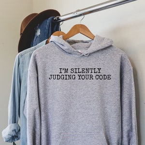 May include: Gray hooded sweatshirt with the text "I'm silently judging your code" printed on the front.