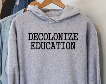 May include: A gray hooded sweatshirt with the text "DECOLONIZE EDUCATION" printed in black on the front.