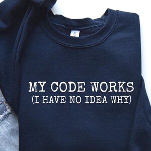 May include: A navy blue sweatshirt with the text "MY CODE WORKS (I HAVE NO IDEA WHY)" printed in white.