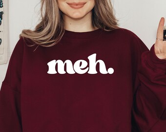 May include: A maroon sweatshirt with the word "meh." printed in white retro-style lettering.