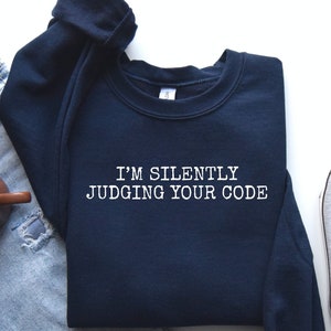 May include: A navy blue sweatshirt with the text "I'm silently judging your code" in white.