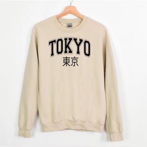 May include: A beige sweatshirt with black text that reads "TOKYO" and "東京" in Japanese.