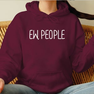 Może przedstawiać: Bordowa bluza z kapturem z białym nadrukiem "EW, PEOPLE".
