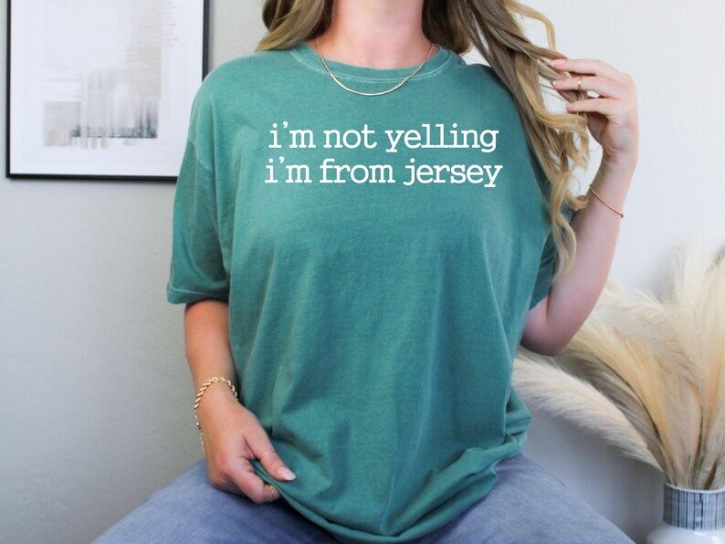 May include: A teal green t-shirt with the text "i'm not yelling i'm from jersey" in white.