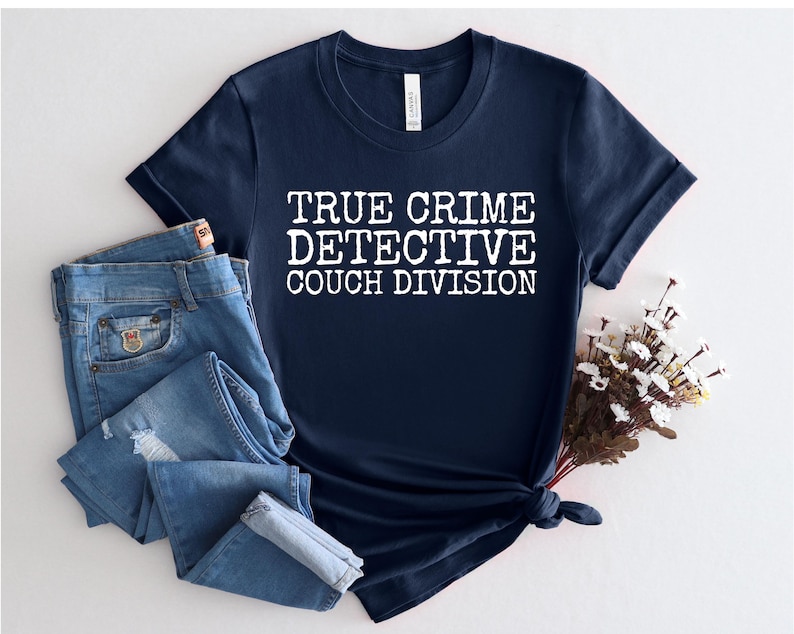 K&ouml;nnte beinhalten: Ein marineblaues T-Shirt mit wei&szlig;em Text, der "True Crime Detective Couch Division" lautet.