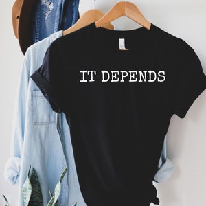 May include: Black t-shirt with white text that reads "IT DEPENDS" in a typewriter font.