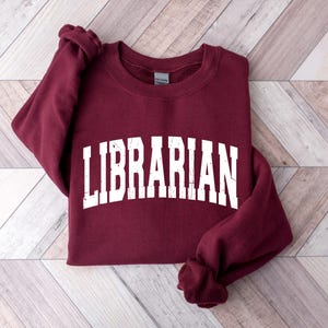 May include: A maroon sweatshirt with the word "LIBRARIAN" printed in white on the front.