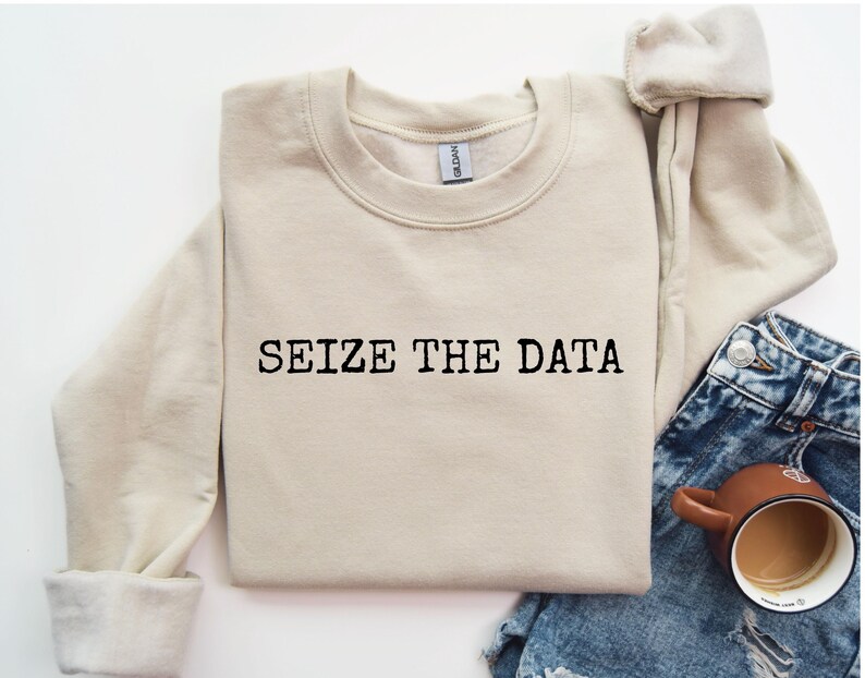 K&ouml;nnte beinhalten: Ein beiger Pullover mit dem Aufdruck "SEIZE THE DATA" in Schwarz auf der Vorderseite.