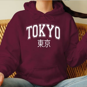 May include: A maroon hoodie with a white print that says "TOKYO" in a collegiate font and "東京" in Japanese characters.