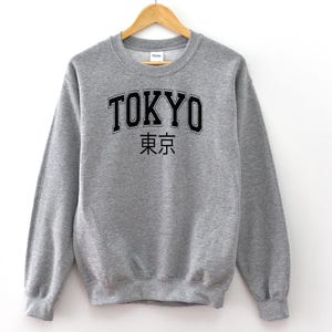 May include: A grey sweatshirt with the word "TOKYO" in black lettering and the Japanese characters for "Tokyo" underneath.