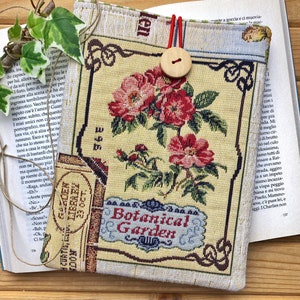 May include: A beige book cover with a floral pattern and the text "Botanical Garden". The cover has a red button and a brown button.