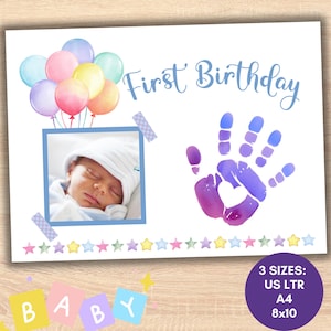 Puede incluir: Una tarjeta de primer cumpleaños imprimible con una ilustración de acuarela de globos de colores y una huella de mano de bebé. La tarjeta también incluye un espacio para una foto y el texto "Primer cumpleaños".