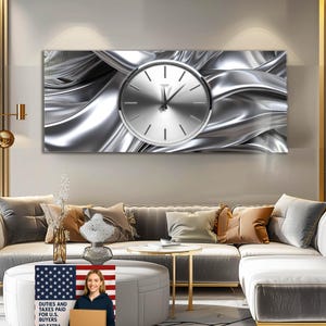 Può includere: Una grande opera d'arte murale rettangolare con un quadrante argentato su uno sfondo di tessuto argentato metallico fluente. L'orologio ha un design minimalista con linee semplici per gli indicatori delle ore e le lancette.