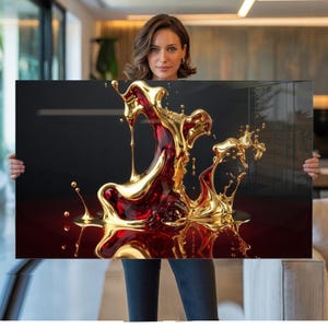 May include: A rectangular wall art print featuring a dynamic, abstract design. The artwork showcases a splash of liquid in shades of gold and deep red against a dark background. The liquid appears to be in motion, with droplets and flowing forms.