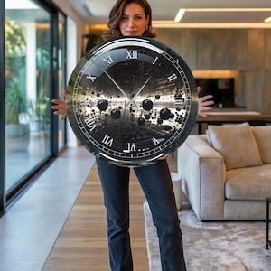May include: A large, round wall clock with a black face and Roman numeral hour markers. The clock's face features a unique, abstract design with a reflective, tunnel-like appearance. The clock is held by a person.