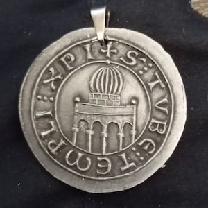 Pode incluir: Um pingente de prata com um design circular que apresenta um edif&iacute;cio com uma c&uacute;pula e arcos. O pingente tem a inscri&ccedil;&atilde;o "S:T:V:B:I:G:E:M:P:I" ao redor da borda.