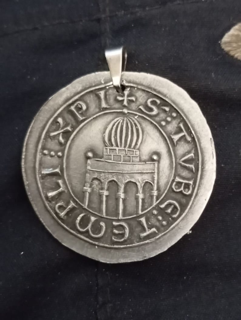 Pode incluir: Um pingente de prata com um design circular que apresenta um edif&iacute;cio com uma c&uacute;pula e arcos. O pingente tem a inscri&ccedil;&atilde;o "S:T:V:B:I:G:E:M:P:I" ao redor da borda.