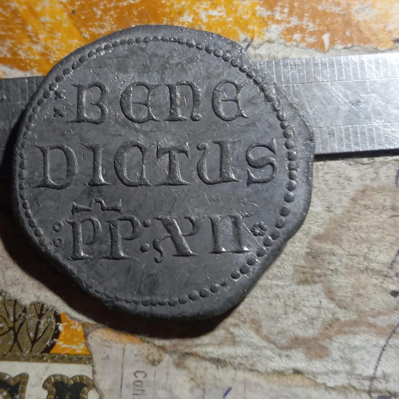 Może przedstawiać: Srebrny metalowy token z napisem "BENE DICTUS PP: XII" w okrągłym wzorze.