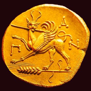 Peut inclure: Une pièce de monnaie circulaire en or présentant le relief d'une créature ailée à cornes tenant une longue lance dans sa gueule. Sous la créature se trouve un épi de blé horizontal. Les lettres A, N et un symbole grec sont visibles.