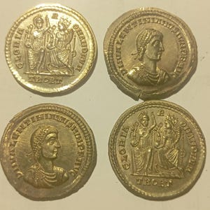 Puede incluir: Cuatro monedas antiguas de oro. Dos monedas presentan dos figuras con el texto "GLORIA ROMANORVM". Las otras dos monedas muestran un perfil de una persona con texto alrededor del borde. Las monedas son circulares y tienen detalles intrincados.