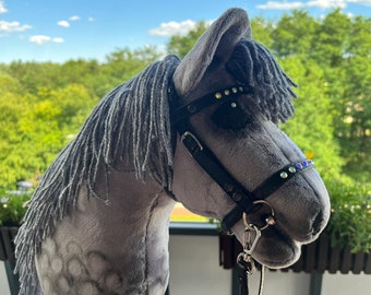 May include: A gray plush horse head with a black leather bridle and rhinestones. The horse has a long gray mane and a black nose.