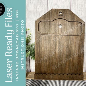 May include: A wooden laser-cut file holder with a decorative top and scalloped bottom edge. The holder has a rectangular cutout and a small hole at the top. The text "Laser Ready Files" is visible on the left side.
