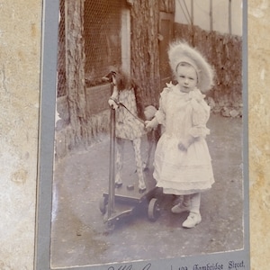 Antique , vintage,  Photo Card In plastic frame of Dressed up girl with a wooden rolling horse cart pull toy